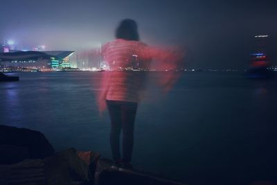 Man standing by sea against sky at night