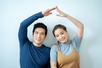 Portrait of smiling young couple against white background