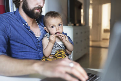 Portrait of baby boy with father using laptop at home