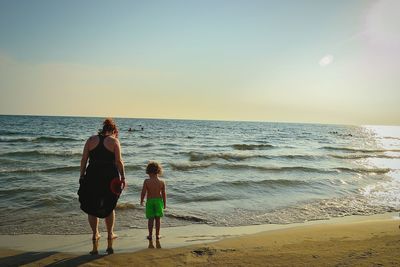 Rear view of women on beach against sky