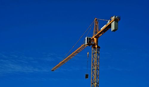 Low angle view of crane against clear blue sky