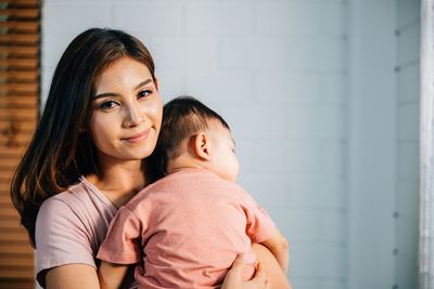 Portrait of young woman standing against wall