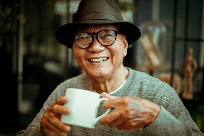 Portrait of smiling senior man having coffee while sitting in cafe