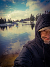 Portrait of man by lake against sky