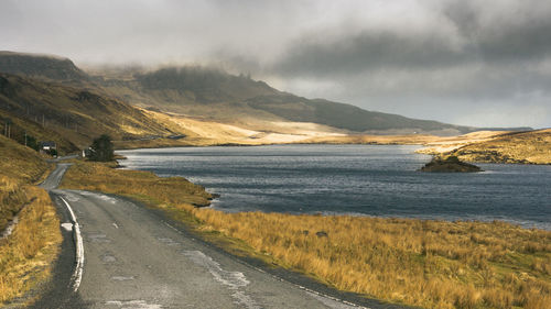 Scenic view of road by sea against sky