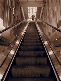 Low angle view of people on escalator in illuminated building