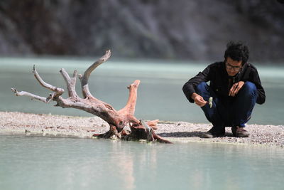 Full length of man crouching on shore at beach