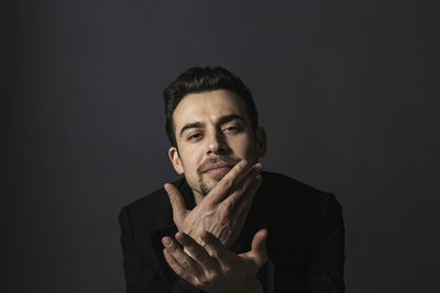 Portrait of young man standing against black background