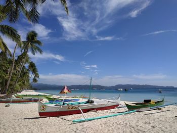 Sailboats moored on beach against sky