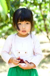 Portrait of cute girl holding smart phone outdoors