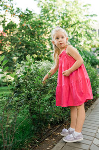 Portrait of young woman standing against plants