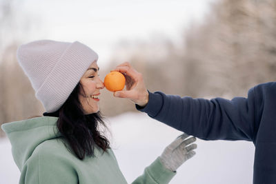 Happy couple playing winter game in forest outdoors. girlfriend with boyfriend funny 