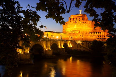 Castel santangelo by tiber river in city at dusk