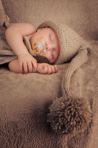 Close-up of cute baby boy sleeping with pacifier on bed at home