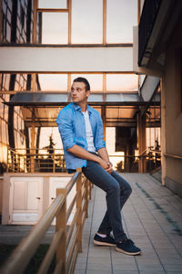 Young man looking away while sitting outdoors