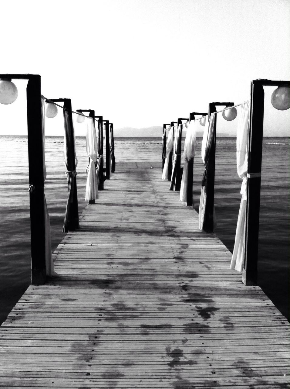 sea, water, horizon over water, beach, in a row, pier, clear sky, wood - material, tranquil scene, the way forward, tranquility, sand, wooden, diminishing perspective, wood, copy space, empty, railing, wooden post, scenics