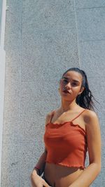 Portrait of young woman standing against wall