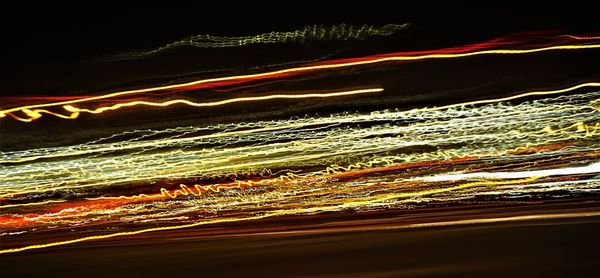 Light trails in sea against sky at night