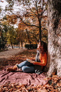 Woman sitting in park during autumn