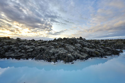 Picturesque scenery of geothermal lake with rocky coast at sunset