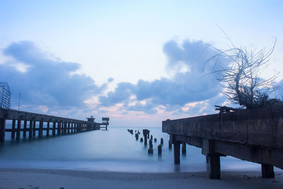 Pier on sea against cloudy sky