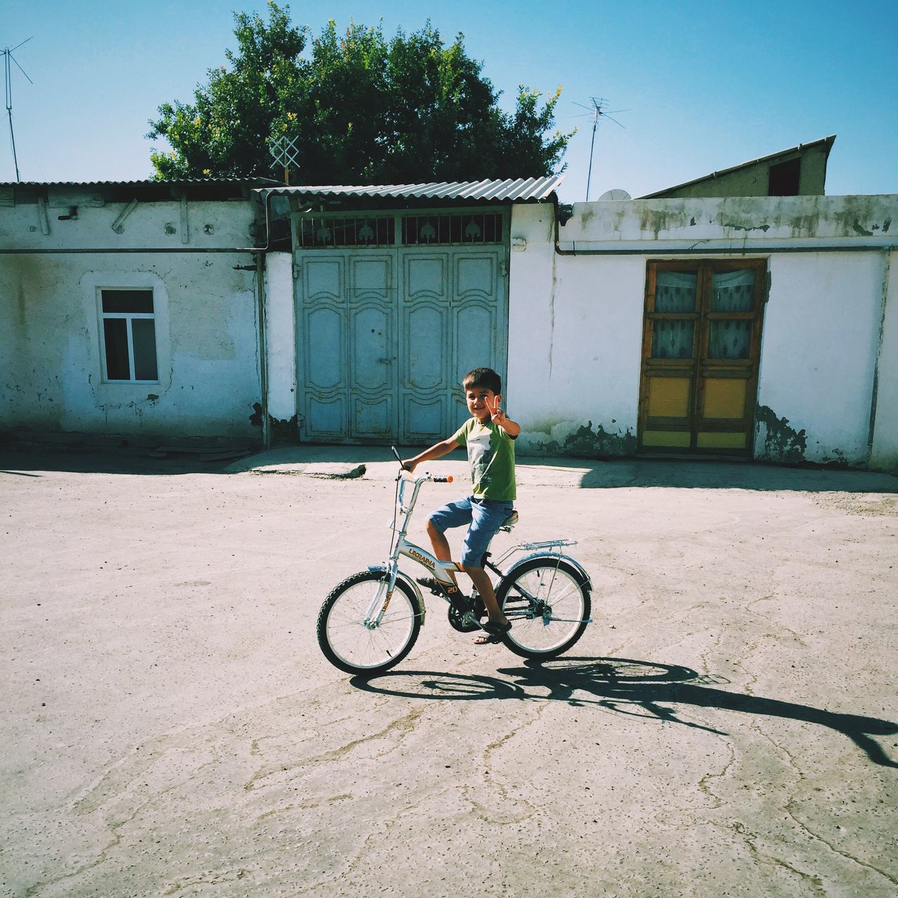 bicycle, building exterior, full length, architecture, built structure, lifestyles, transportation, land vehicle, mode of transport, leisure activity, riding, men, casual clothing, side view, street, young adult, day, sunlight