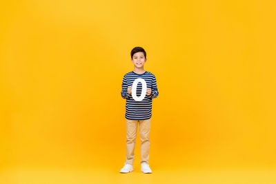 Portrait of boy standing against yellow background
