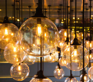 Close-up of illuminated light bulb hanging at night