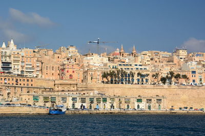Buildings by sea against sky in city