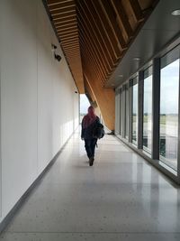 Rear view of man walking in corridor of building