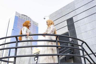 Young woman talking with friend while standing at staircase