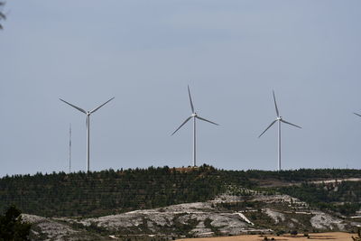 Wind turbines on field against sky