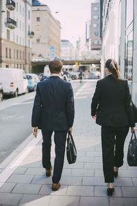 Rear view of business people walking on sidewalk