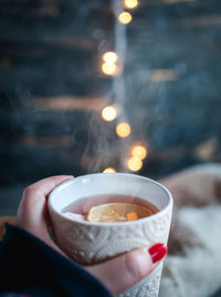 Close-up of hand holding a cup of christmas tea with lemon