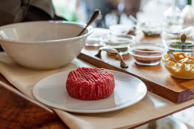 Close-up of professional chef making steak tartare on trolley with spices and ingredients