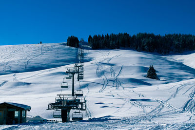 Scenic view of snow covered mountains against clear blue sky