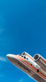 Low angle view of airplane against clear blue sky