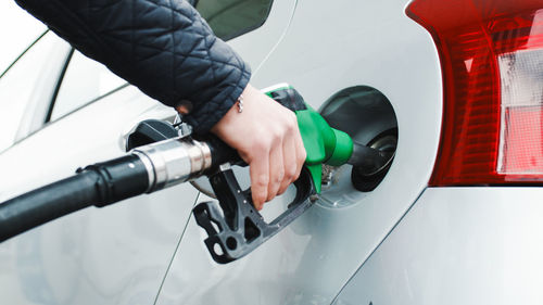 Hand of a gas station man is putting gasoline into a car