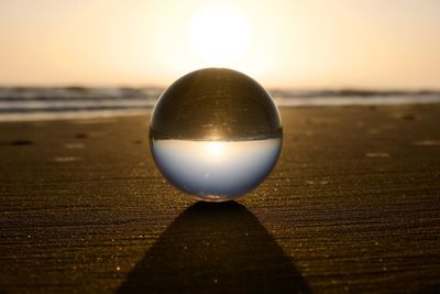 Close-up of crystal ball at beach during dawn