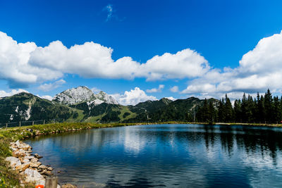 Scenic view of lake by trees against blue sky