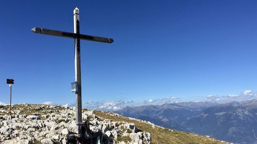 Cross on mountain against clear blue sky