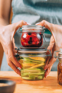 Woman holding jars with fermented fruits.