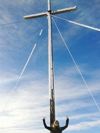 Happy woman standing by mast against sky