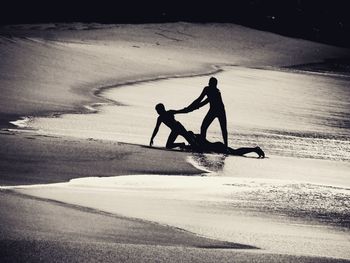 Silhouette man with bicycle on beach against sky