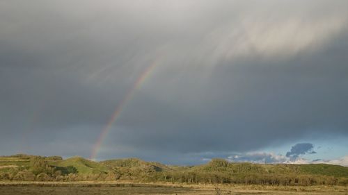 Rainbow over landscape against sky