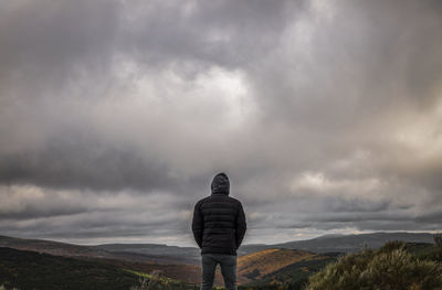 Rear view of adult man on top of mountain against cloudy sky, in tejera negra, guadalajara, spain