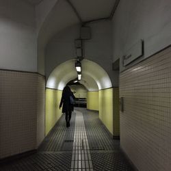 Rear view of people walking in tunnel