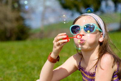 Girl blowing bubbles while standing at park