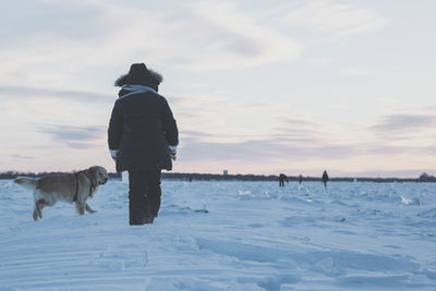 Rear view of man standing on snow covered landscape
