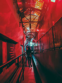 Rear view of man walking in illuminated corridor